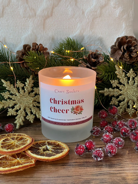 A lit deluxe scented candle made from vegetable wax on a Christmas decoration background