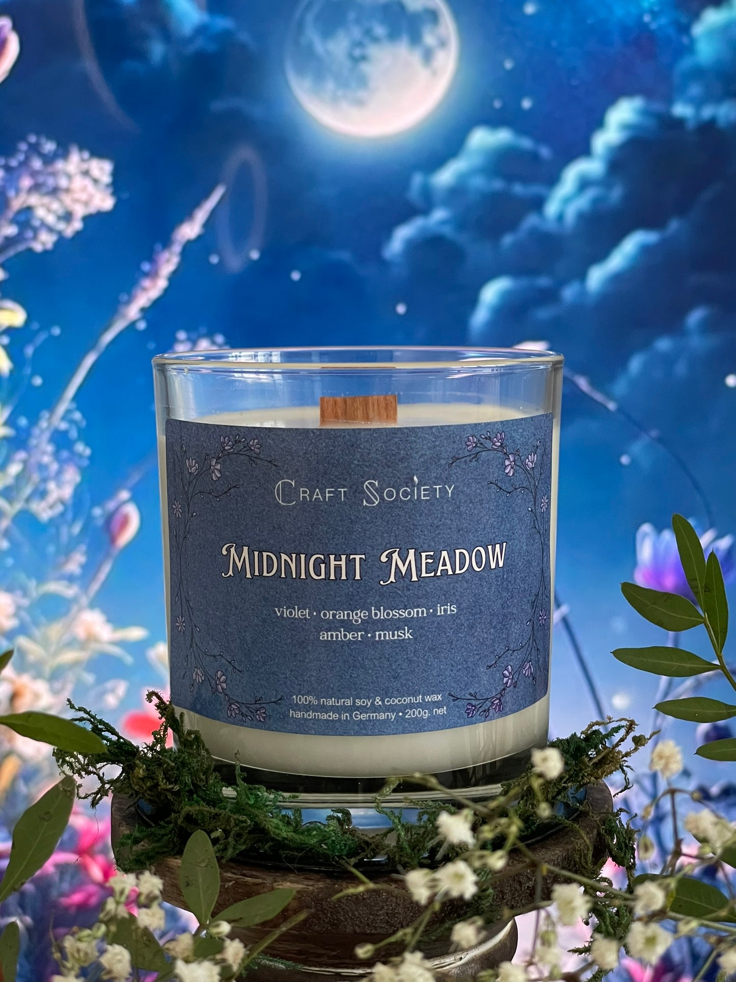 A scented candle called Midnight Meadow on a floral and night background, unlit, clear glass jar, deluxe version with wooden wick