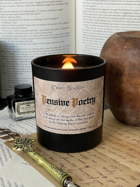 A burning deluxe scented candle with an black jar on a dark academia background
