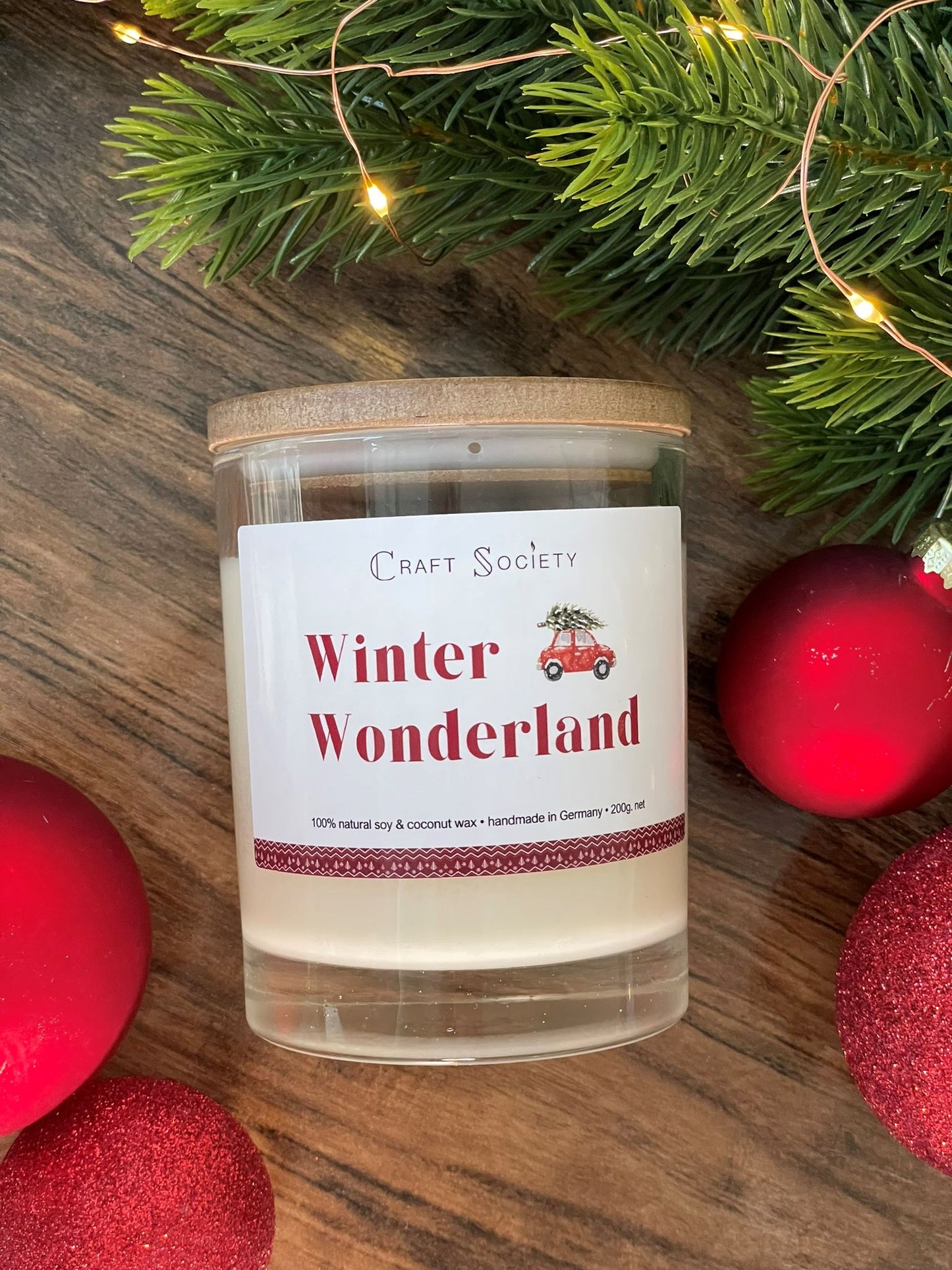 The Winter Wonderland scented candle in a clear glass jar on a winter decorated background