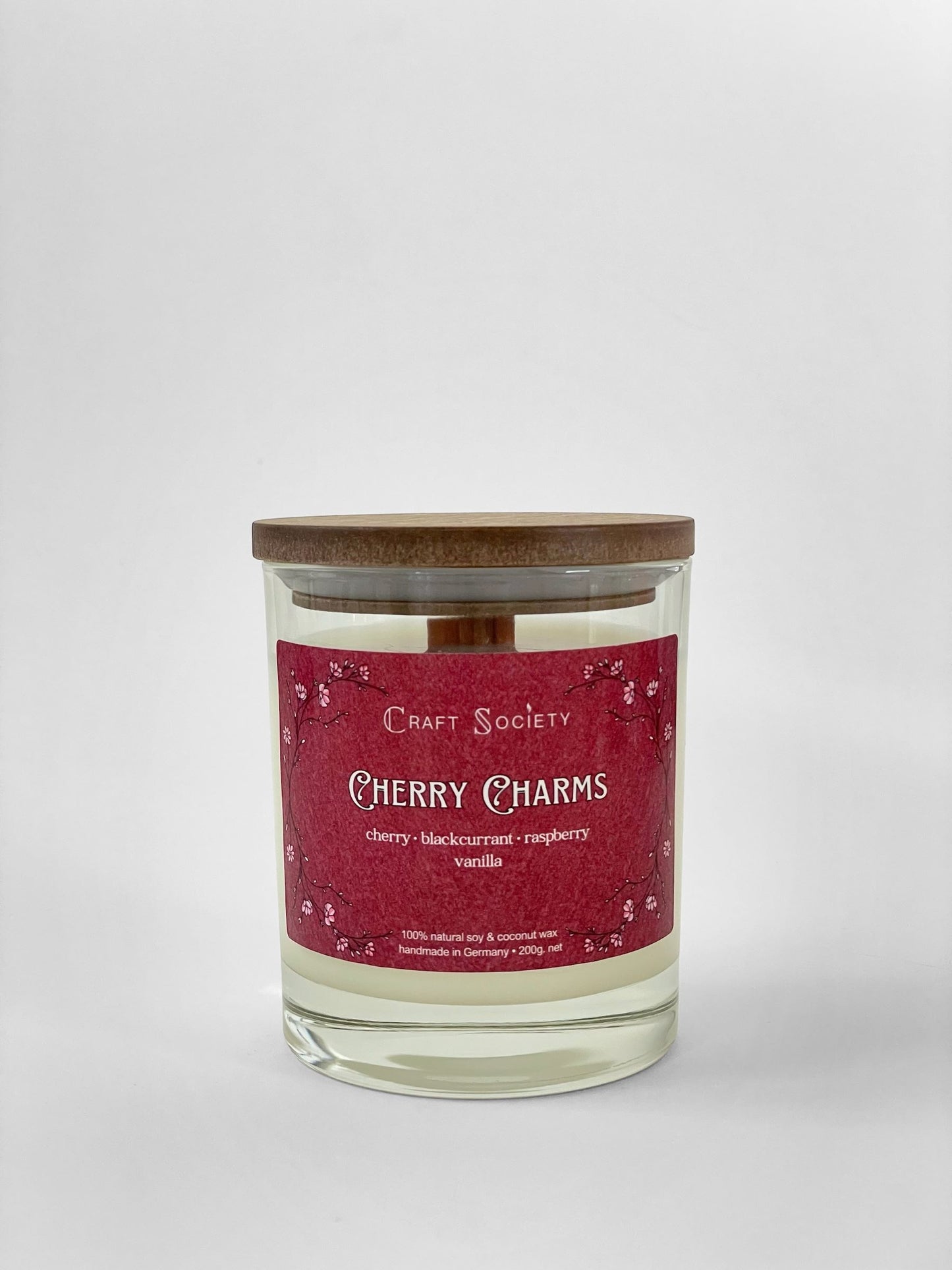 A scented candle called Cherry Charms on a white background, box, clear glass jar, deluxe version with wooden wick