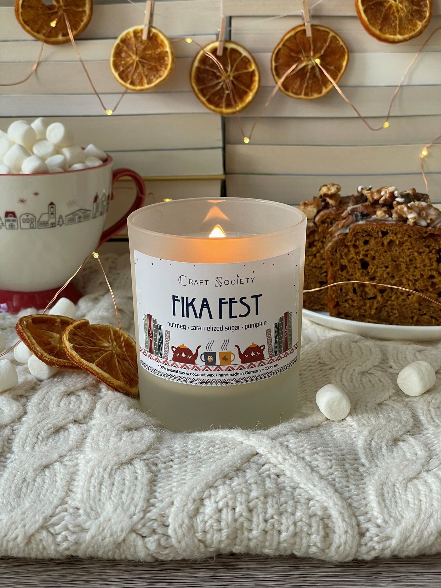 A burning deluxe scented candle on a decorated background