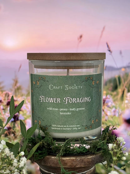 A scented candle called Flower Foraging on a floral and sunrise background, boxed, clear glass jar, regular version with cotton wick