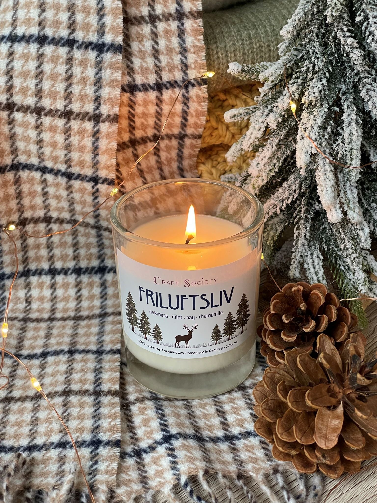 A burning scented candle on a decorated background with pine cones