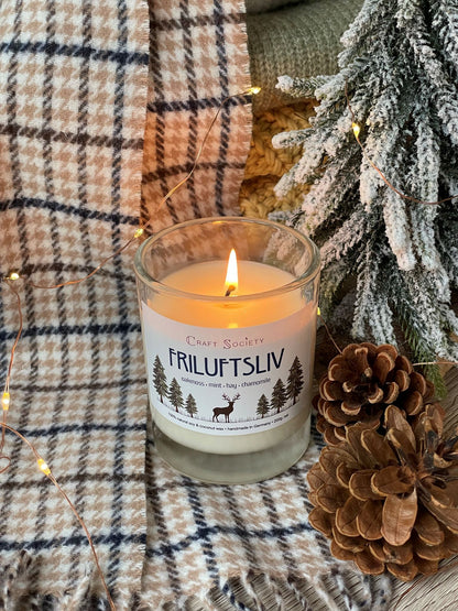 A burning scented candle on a decorated background with pine cones