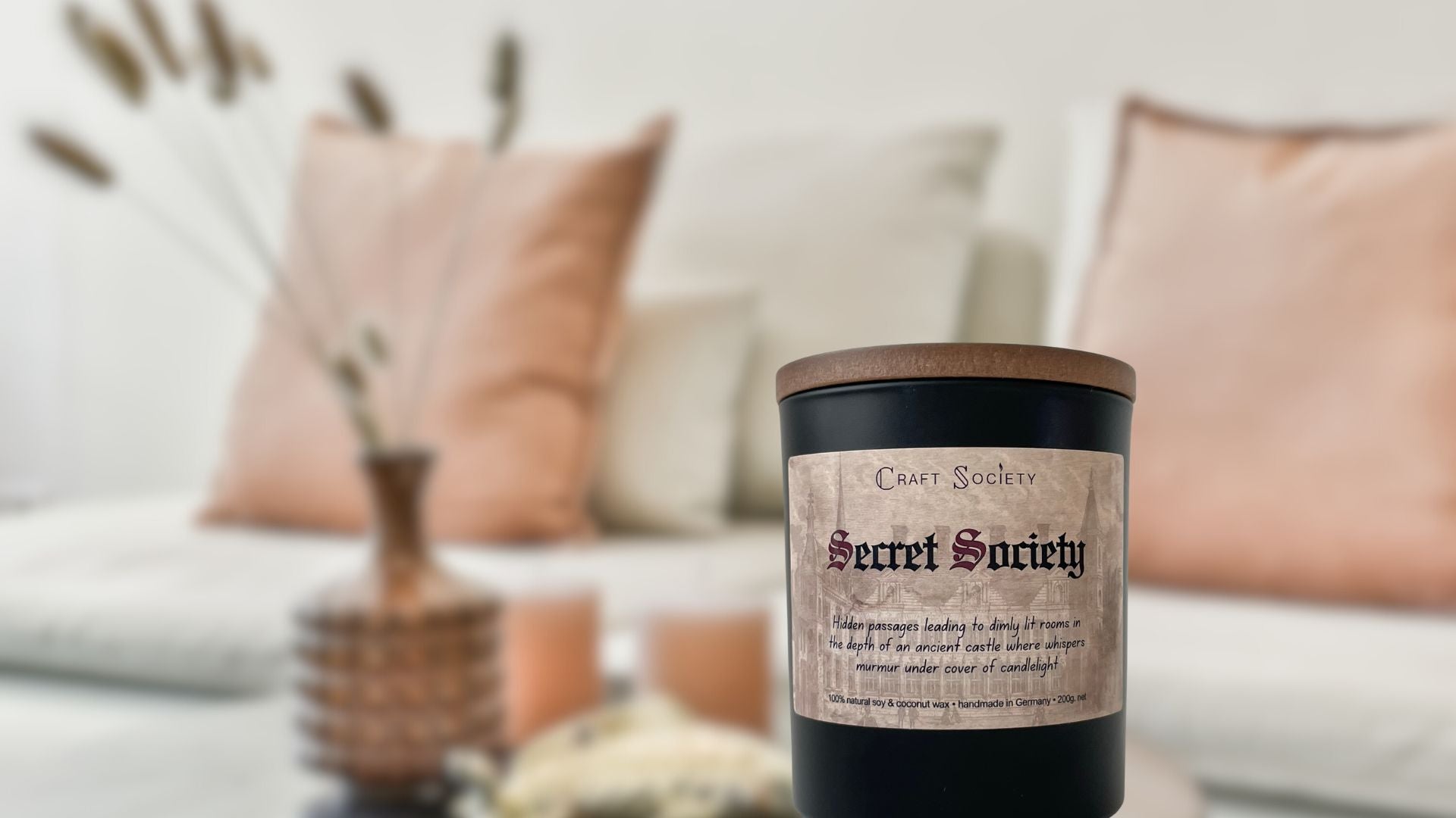 A deluxe scented candle called Secret Society on a cosy room background