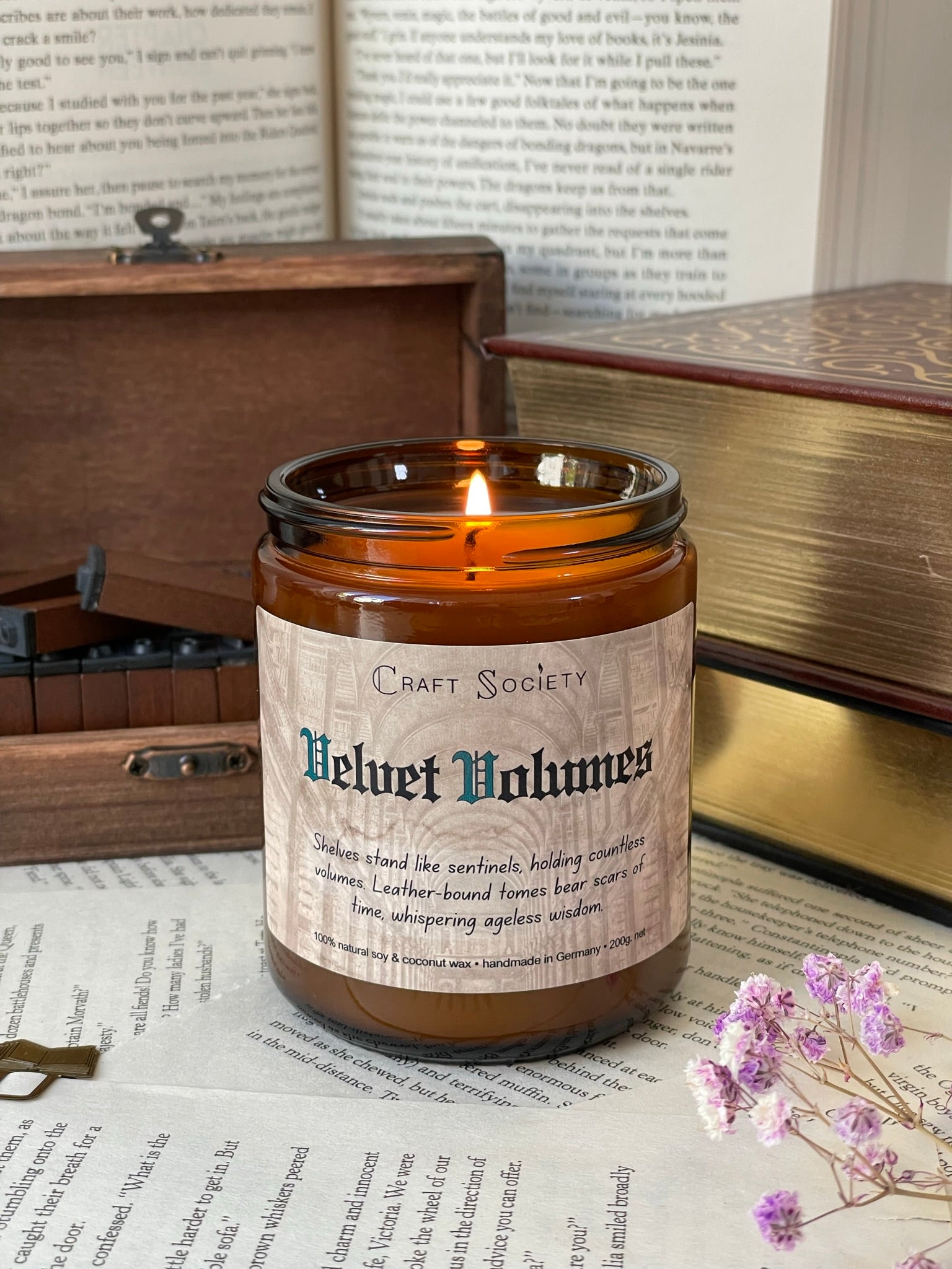 A burning scented candle in an amber jar on a decorated background with books and texts